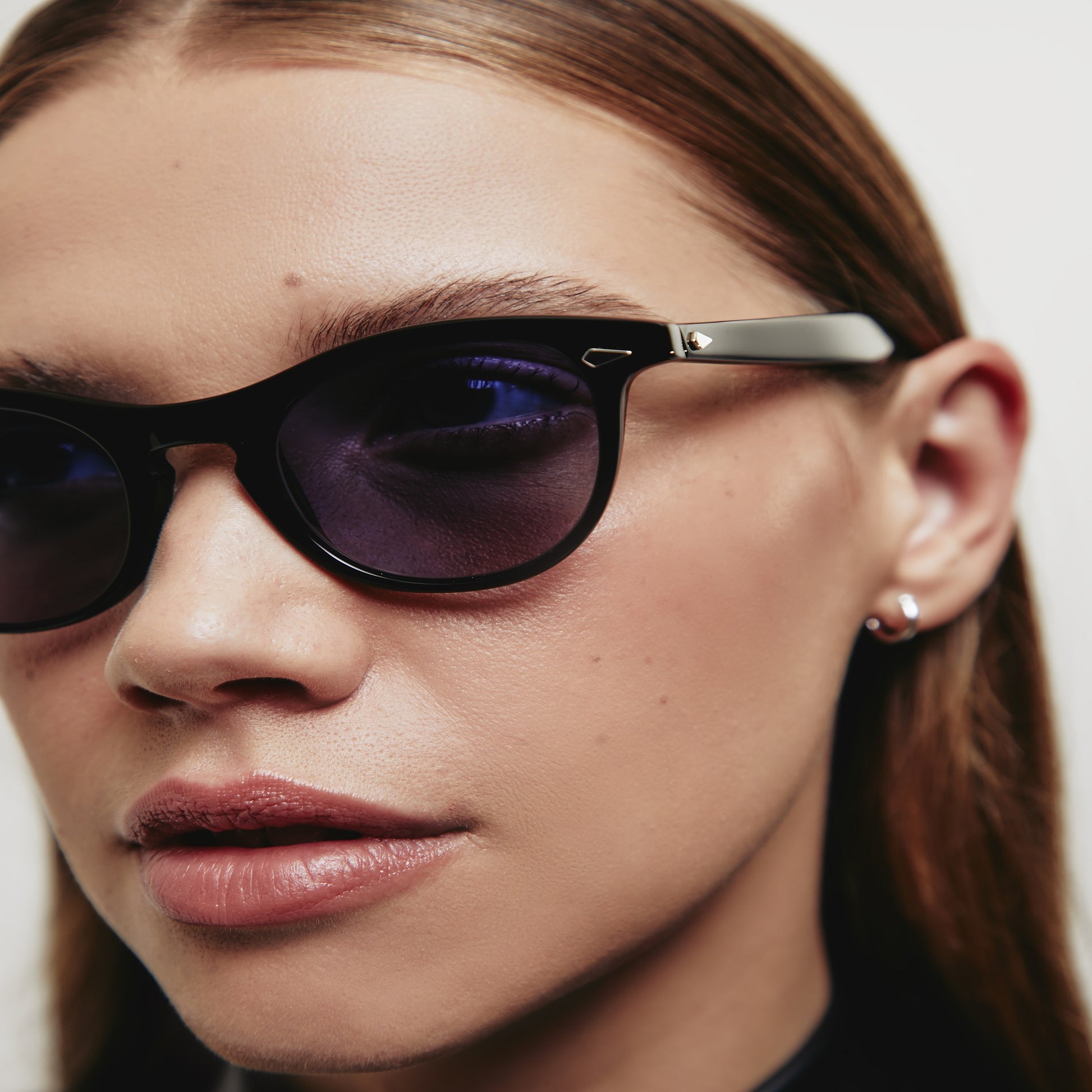 A person wearing the glossy black Leading Liz frame, the luxury cat-eye fashion glasses.